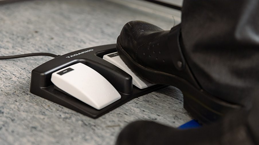 Microscope operator using a footswitch to improve microscope ergonomics