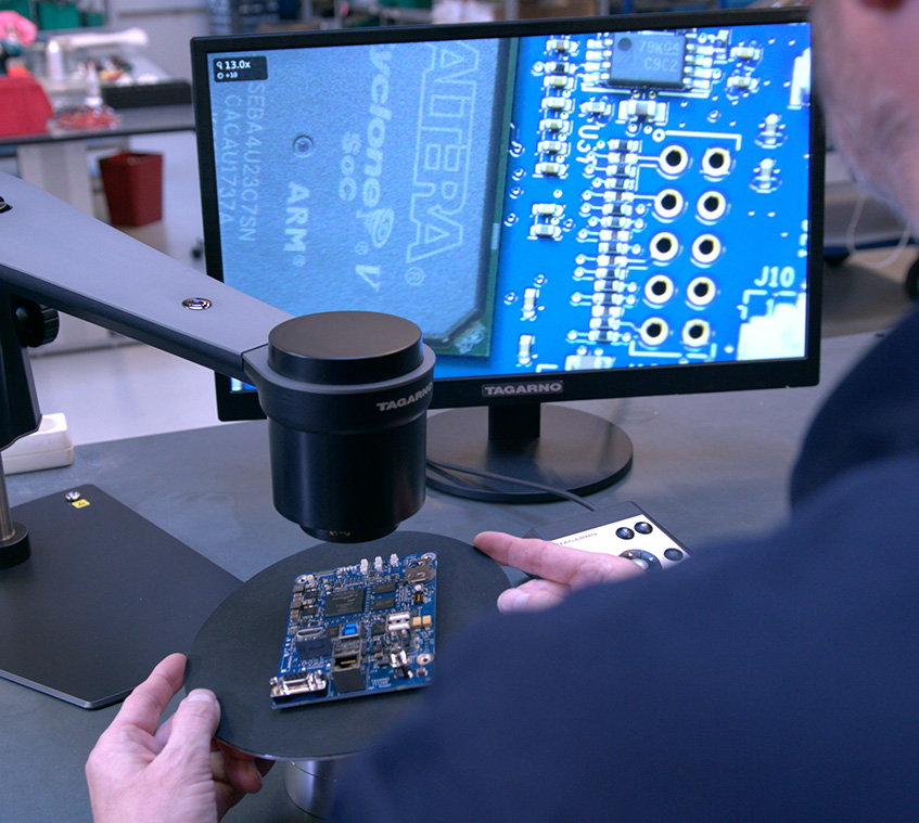 Male microscope operator inspecting PCB on digital microscope