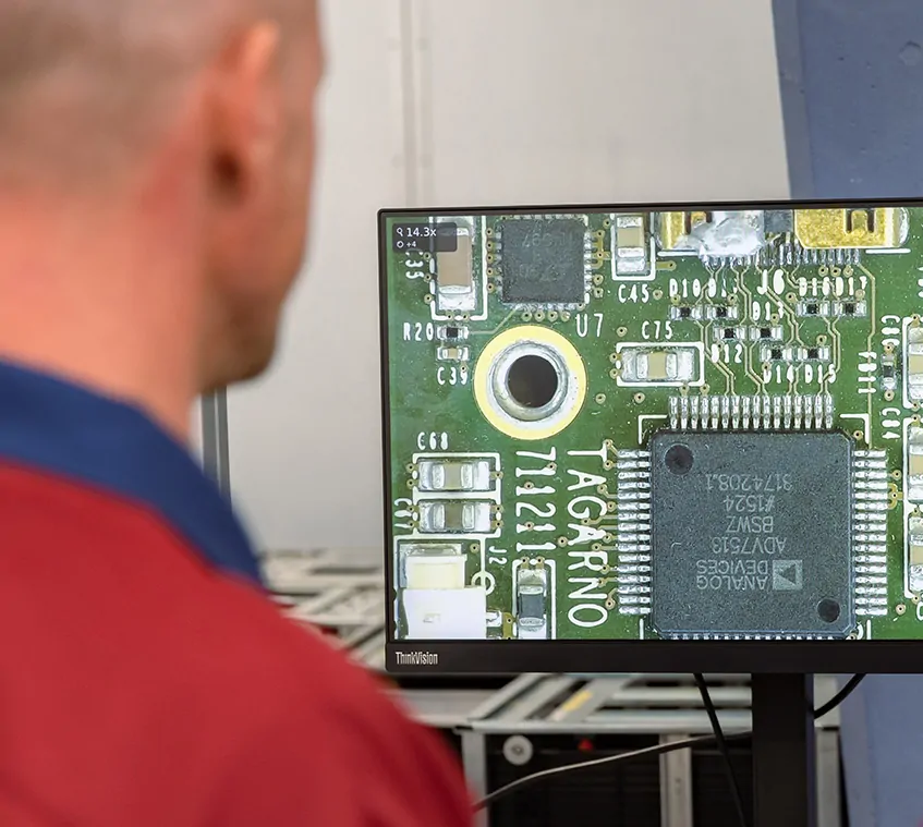 Man inspecting a PCB under a digital microscope