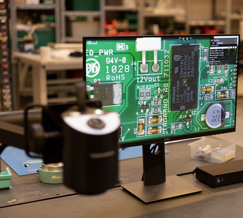 Woman using microscope with camera to inspect PCBs