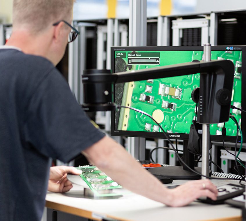 Man using a microscope with a camera to inspect PCBs